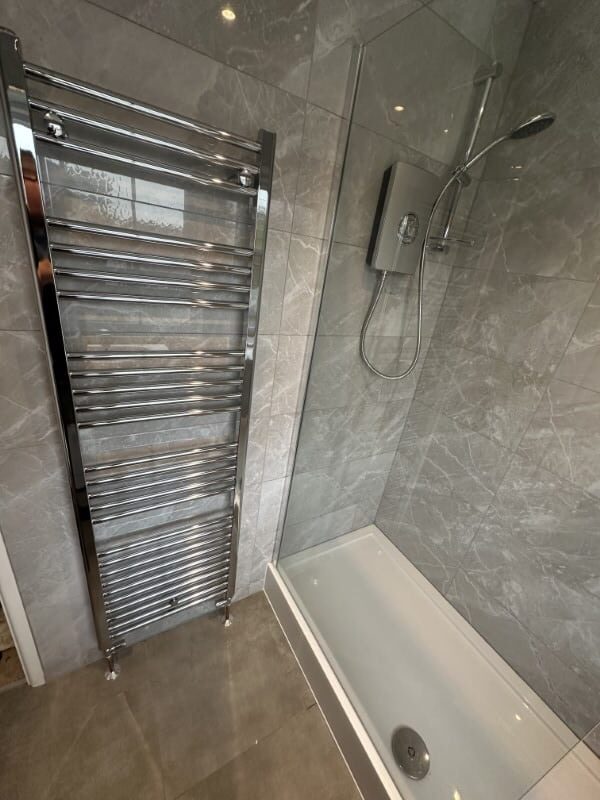 Modern bathroom with a walk-in shower and a chrome towel radiator.