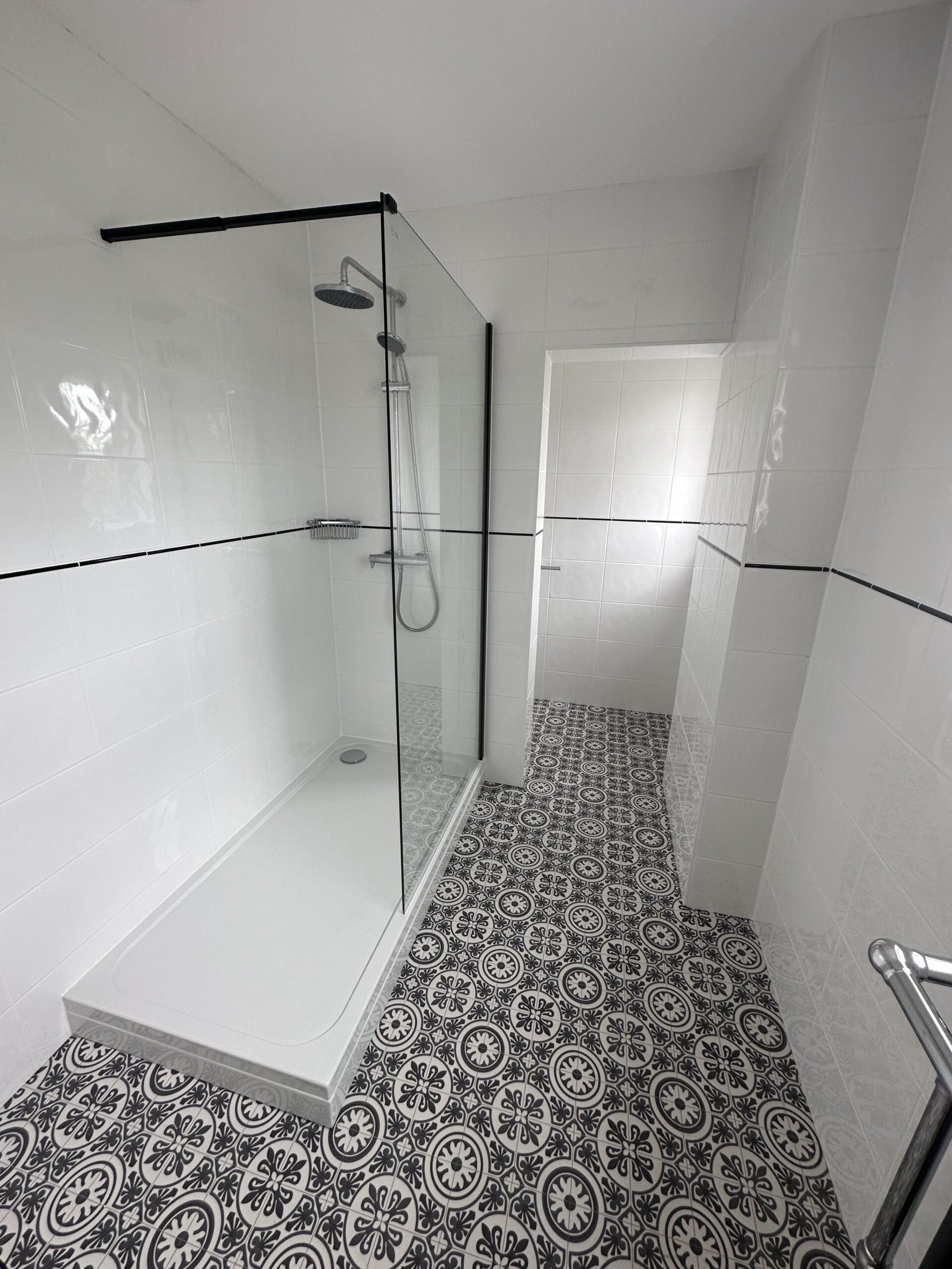 PatternedTiles Bathroom with black and white patterned floor tiles and a modern glass shower enclosure.