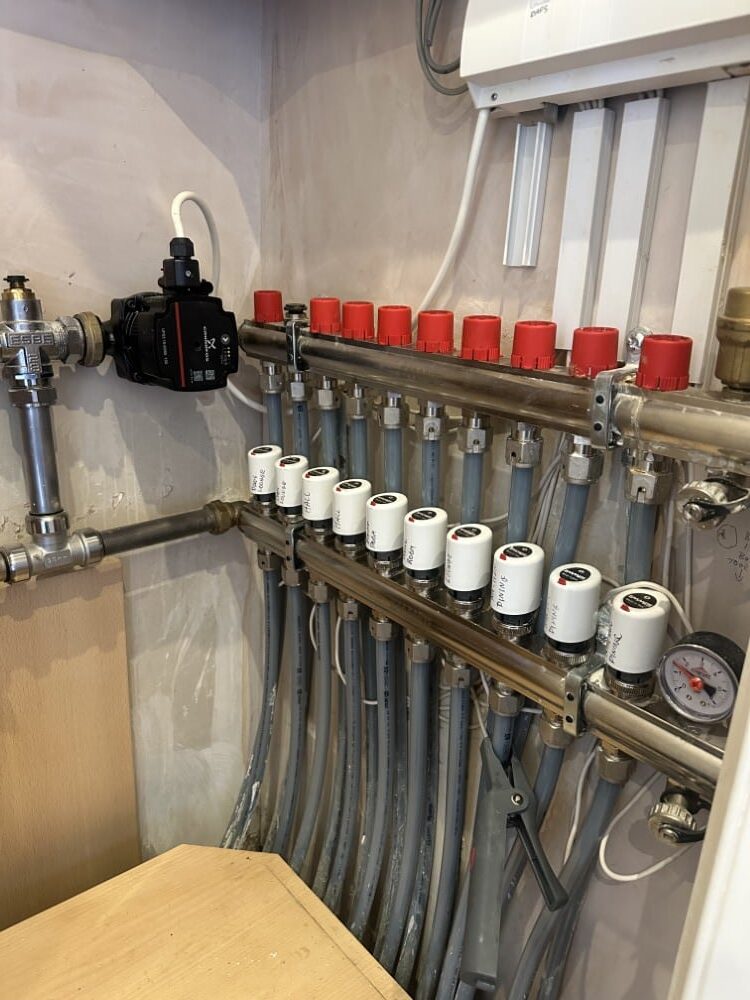 A set of plumbing pipes and valves connected to a control system on a wall.