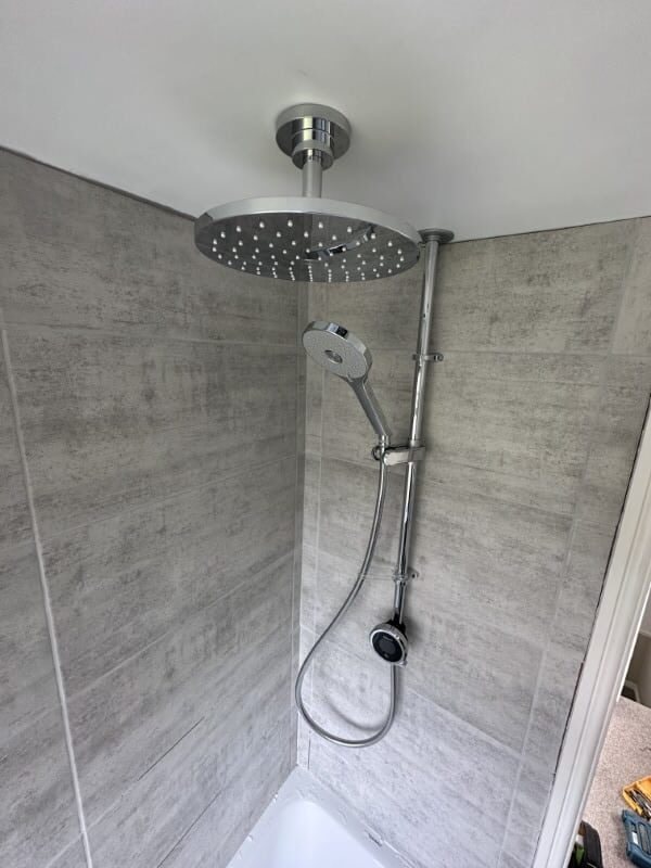 Modern rainfall shower with a handheld shower head in a tiled bathroom corner.