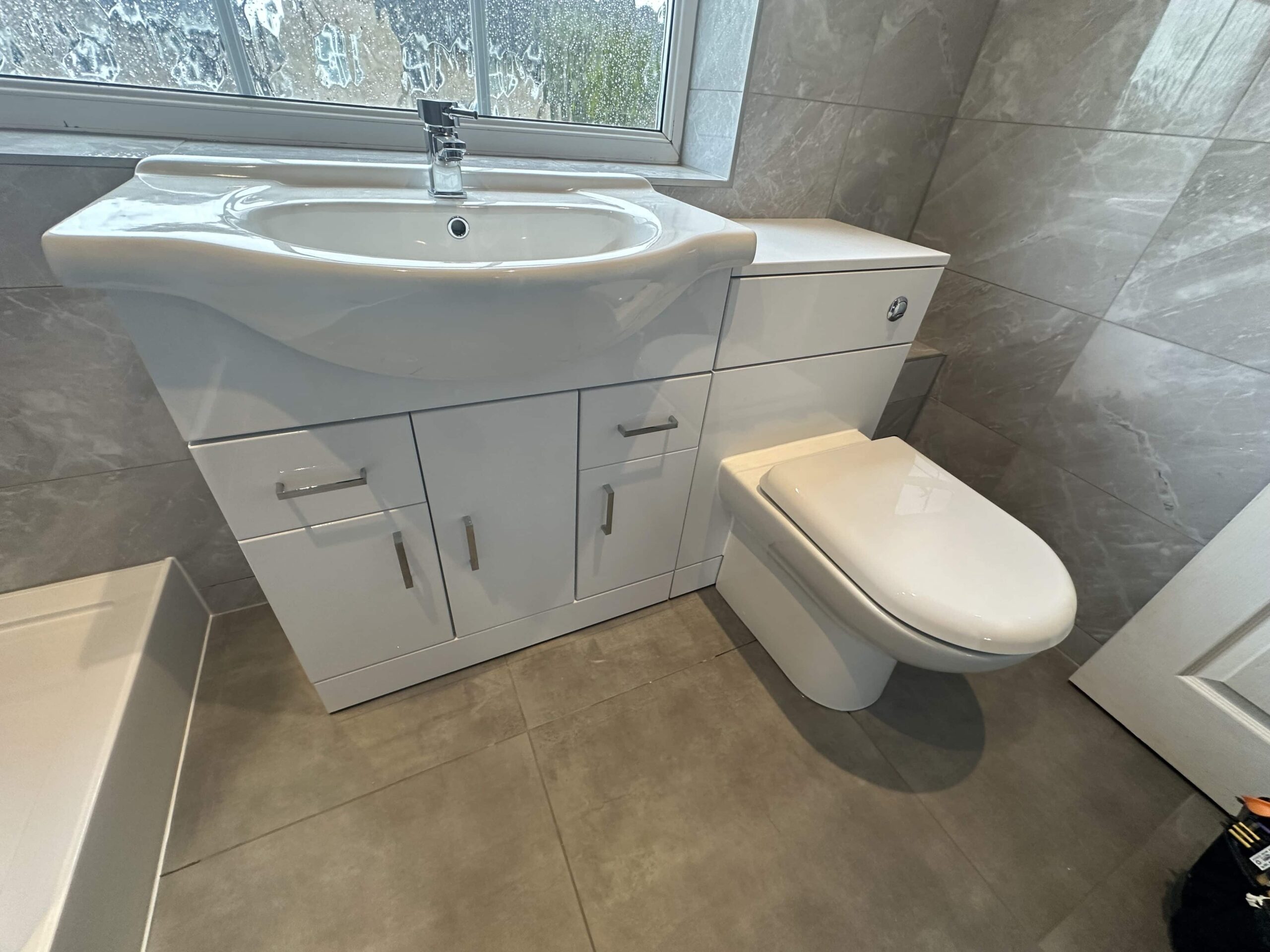 WhiteBathroom Modern white bathroom with a sink, cabinet, and toilet on gray tile floor.